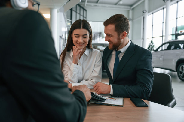 一家人正在买新车。三个人在汽车陈列室里一起工作图片下载