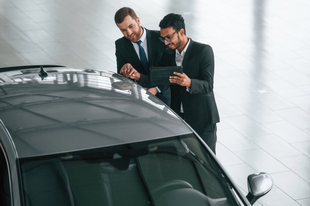 灰色汽车表面检查。两个商人在汽车陈列室里一起工作图片下载