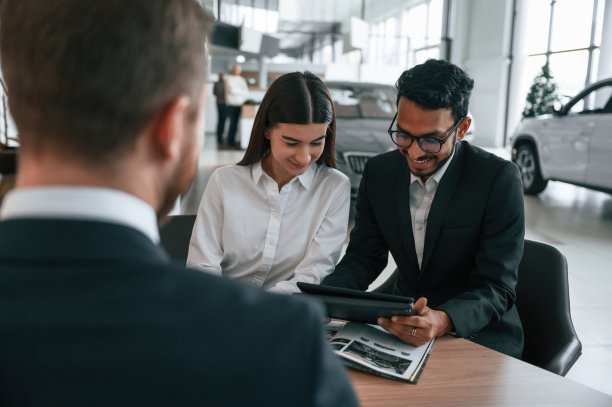 一家人正在买新车。三个人在汽车陈列室里一起工作图片下载