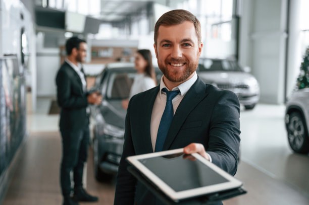 使用图形平板。三个人在汽车陈列室里一起工作图片下载