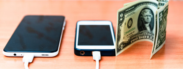 插上电源插座、适配器、电源线、智能手机充电器、纸钱放在木桌附近。智能手机正在充电。图片下载