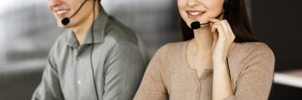 两名戴着耳机的年轻人坐在办公室的办公桌前与客户交谈。关注女性。呼叫中心接线员在工作图片下载