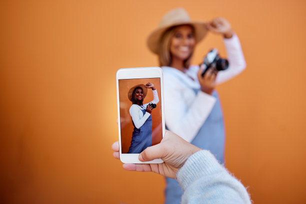 朋友们用手机在社交媒体或数字存储器上拍摄隔离在墙壁背景上的女子。手持智能手机屏幕的快乐档案的z世代，影响者在夏季模型图片下载