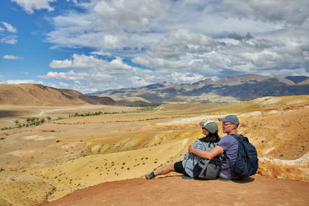几名游客背对着相机坐着，背景是风景图片下载