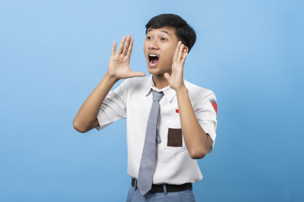 年轻的印尼高中生在蓝色背景下大声尖叫着宣布信息。印尼高中生图片下载