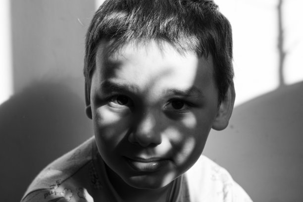 在阳光下微笑的婴儿的黑白肖像。可爱漂亮的男婴看着黑白相机拍摄。阳光照在孩子迷人的脸上。图片下载