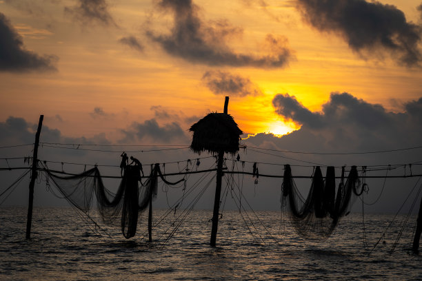在日出期间，越南Tra Vinh省的渔民在海上拉鱼竿上的渔网的剪影，当地人称之为Day hang khoi。图片下载