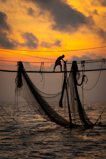 在日出期间，越南Tra Vinh省的渔民在海上拉鱼竿上的渔网的剪影，当地人称之为Day hang khoi。图片下载