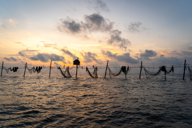 在日出期间，越南Tra Vinh省的渔民在海上拉鱼竿上的渔网的剪影，当地人称之为Day hang khoi。图片下载