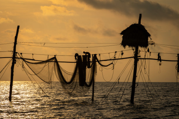 在日出期间，越南Tra Vinh省的渔民在海上拉鱼竿上的渔网的剪影，当地人称之为Day hang khoi。图片下载