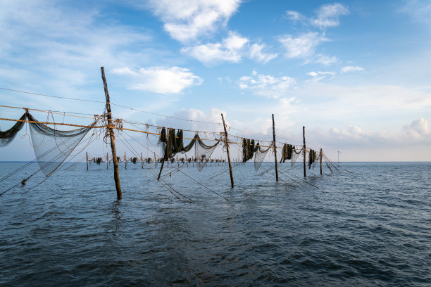 在日出期间，越南Tra Vinh省的渔民在海上拉鱼竿上的渔网的剪影，当地人称之为Day hang khoi。图片下载