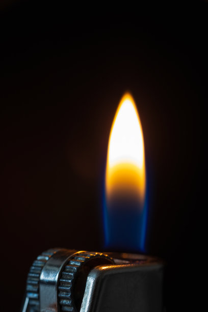 黑色背景上带火的打火机。黑色微距照片图片下载