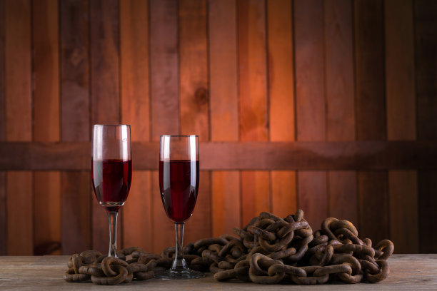 选择性聚焦拍摄了两杯红酒，生锈的链子在木制背景上图片下载