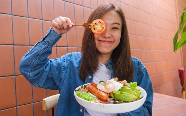 一名年轻女子在吃沙拉时用一片西红柿遮住眼睛图片下载