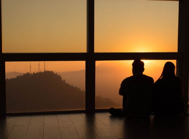 这张照片拍摄的是一对情侣在眺望窗外美丽的日落时拥抱在一起图片下载