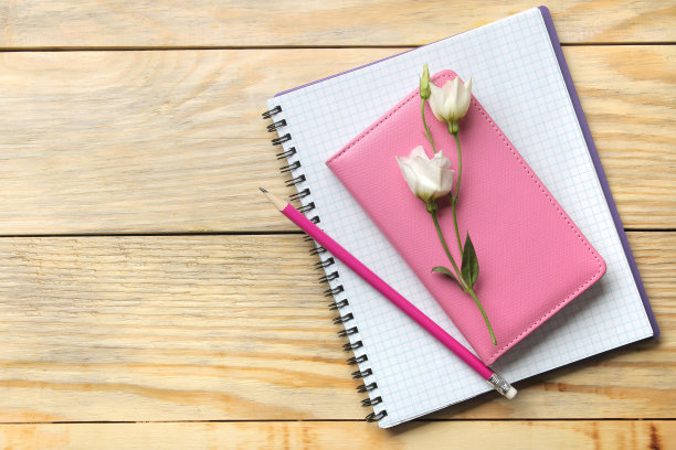 笔记本和铅笔，漂亮的花在一个天然的木桌上。俯视图图片下载