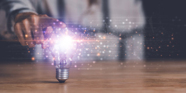 人类的手指向灯泡，寻找解决商业问题的新方案，头脑风暴中的创新和脑力，寻找创造力和灵感，成功的商业想法图片下载