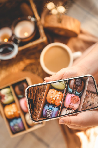 女孩用她的手机拍摄了一个自上而下的各种各样的马卡龙盒子的照片图片下载