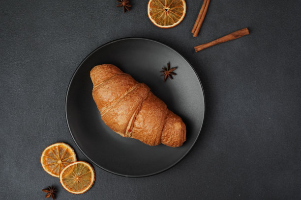 俯视图的美味，新鲜出炉的羊角面包躺在黑色的盘子上，对着黑色的背景图片下载