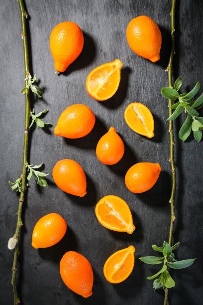 俯视图橙色金桔依偎在绿色树叶和黑色背景图片下载