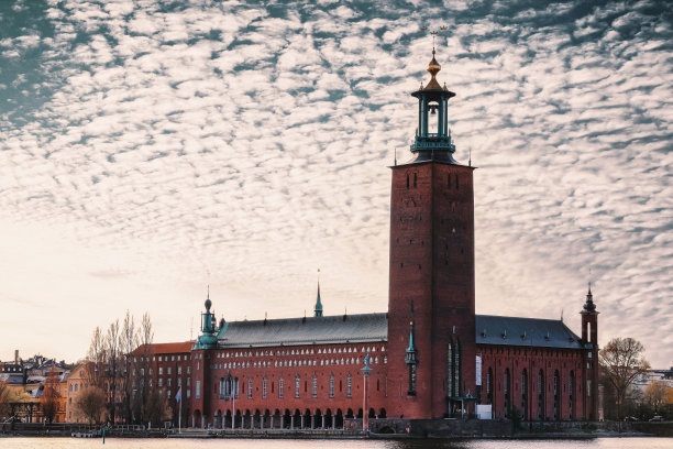 这张令人惊叹的照片展示了一座宏伟的红色建筑，坐落在宁静的蓝色水域上图片下载