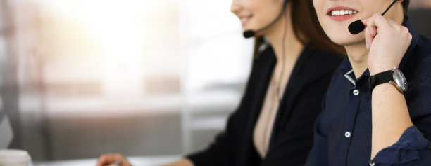 年轻男子戴着耳机正在和客户交谈，而坐在现代阳光充足的办公室。呼叫中心接线员在工作图片下载