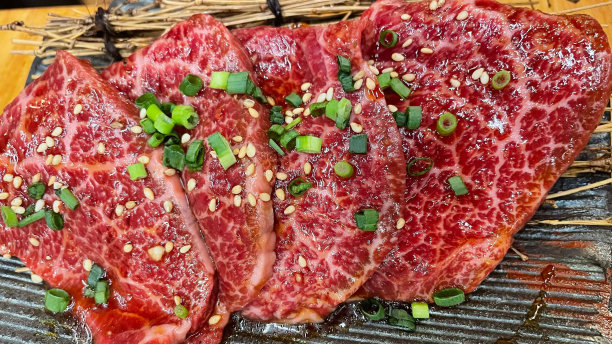 牛排的特写图片，上面有葱和芝麻，背景是烟熏图片下载