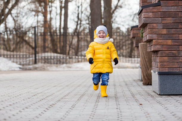 一个穿着黄色胶靴和夹克的4岁小孩的肖像。春天里，孩子在公园里散步。春秋假期的照片。图片下载