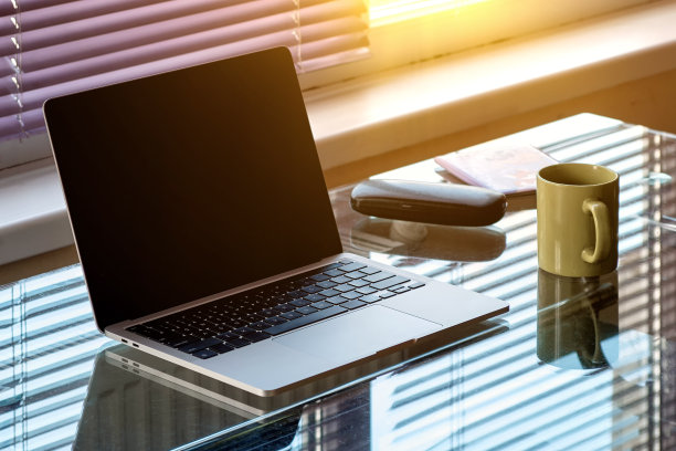 一台打开的笔记本电脑，一张信用卡和一大杯咖啡放在厨房的玻璃桌上。图片下载