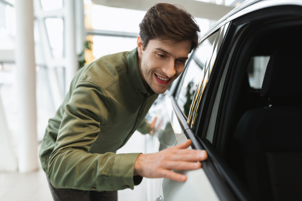 英俊的年轻人检查新车，购买豪华车在汽车经销中心图片下载