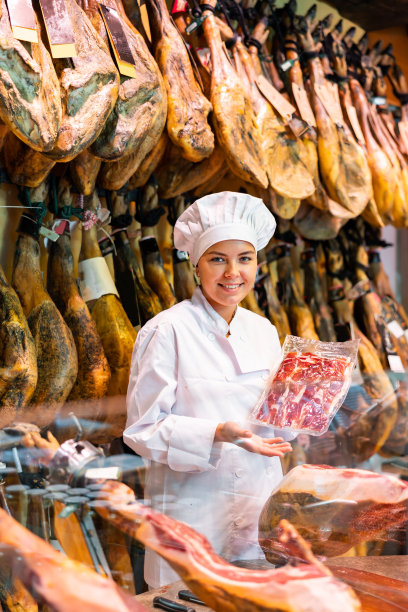 在肉店里，女售货员正在切火腿的整条腿图片下载