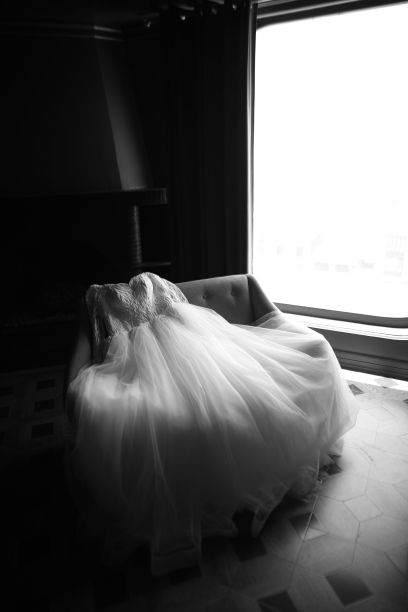 一件灰色的新娘礼服披在阳光明媚的窗户前的椅子上图片下载