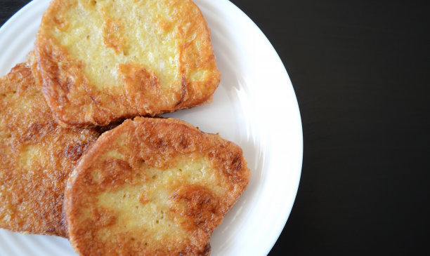 照片上是一个白色的盘子，黑色的木头背景上有面包丁，早餐有烤面包图片下载