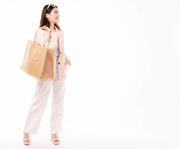 年轻女子在西装和眼镜持有购物袋与购买隔离在白色背景的工作室肖像购物折扣销售年轻的商业女士看着复制空间与快乐和微笑的脸图片下载