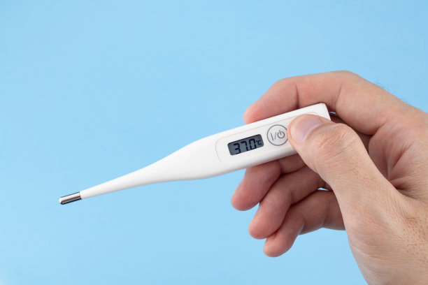 男人的手拿着一个蓝色背景的数字温度计。图片下载