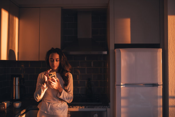 漂亮女孩在厨房用智能手机。图片下载