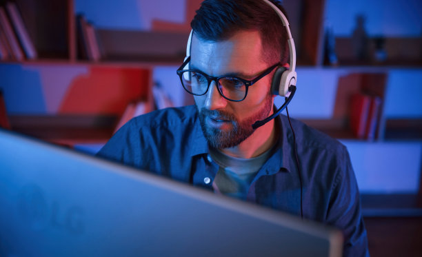 阅读和蓝色霓虹灯照明。一名男子坐在家里的电脑前图片下载