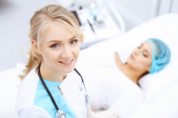 女医生和年轻女病人在医院。医生检查躺在床上的女孩，从上面看图片下载