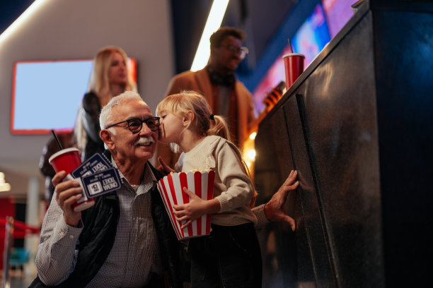 小孩在电影院亲吻爷爷。图片下载