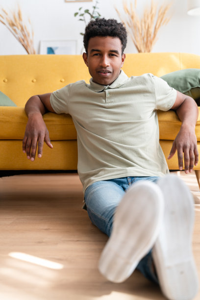 快乐的黑人坐在客厅的地板上图片下载