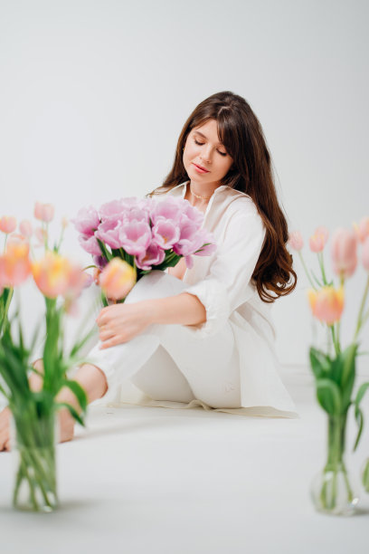 温柔的黑发在白色坐在一束花在地板上的花瓶图片下载