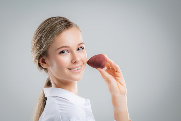 可爱美丽的自然黑发女孩清洁脸用棉花海绵微笑看着相机在白色背景。美容和水疗。图片下载