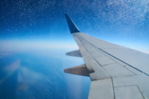 从一架正在着陆的飞机上眺望窗外。一架飞机的机翼在土耳其热带岛屿上空的云层上飞行。飞机的机翼在天空的云层上飞行图片下载