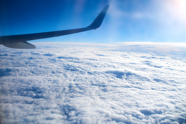 从一架正在着陆的飞机上眺望窗外。一架飞机的机翼在土耳其热带岛屿上空的云层上飞行。飞机的机翼在天空的云层上飞行图片下载