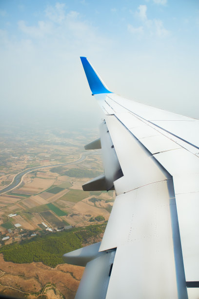 从一架正在着陆的飞机上眺望窗外。一架飞机的机翼在土耳其热带岛屿上空的云层上飞行。飞机的机翼在天空的云层上飞行图片下载