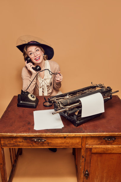 漂亮的女人作家坐在桌子上，在米色背景上热情地打电话图片下载