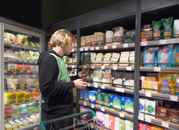 年轻人在超市购物，阅读产品信息。图片下载