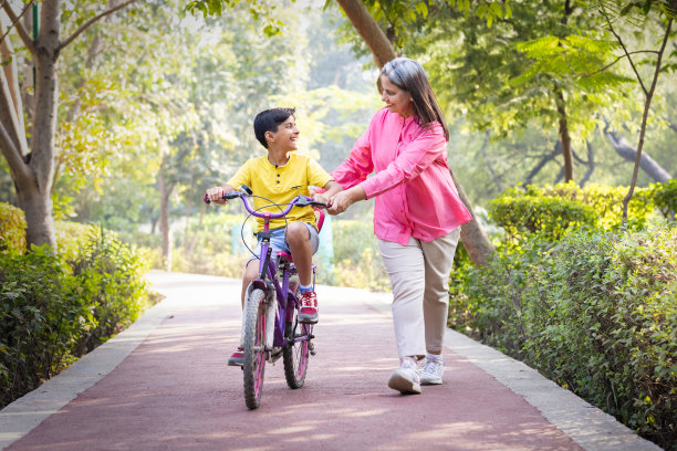 奶奶在公园里帮助顽皮的孙子骑自行车图片下载