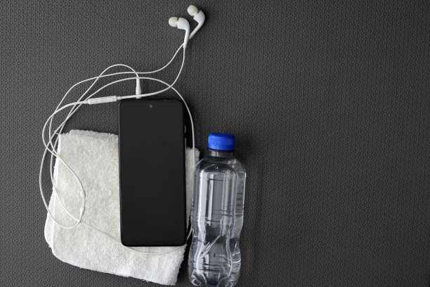 在运动垫上放上必要的物品，如无线耳机、手机、苹果、补水水、汗巾和储物柜钥匙图片下载