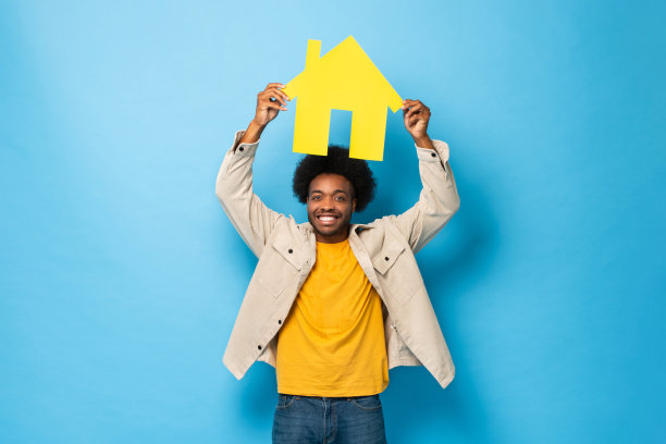 快乐的微笑非洲裔美国人持有的房子剪出孤立的浅蓝色工作室背景图片下载